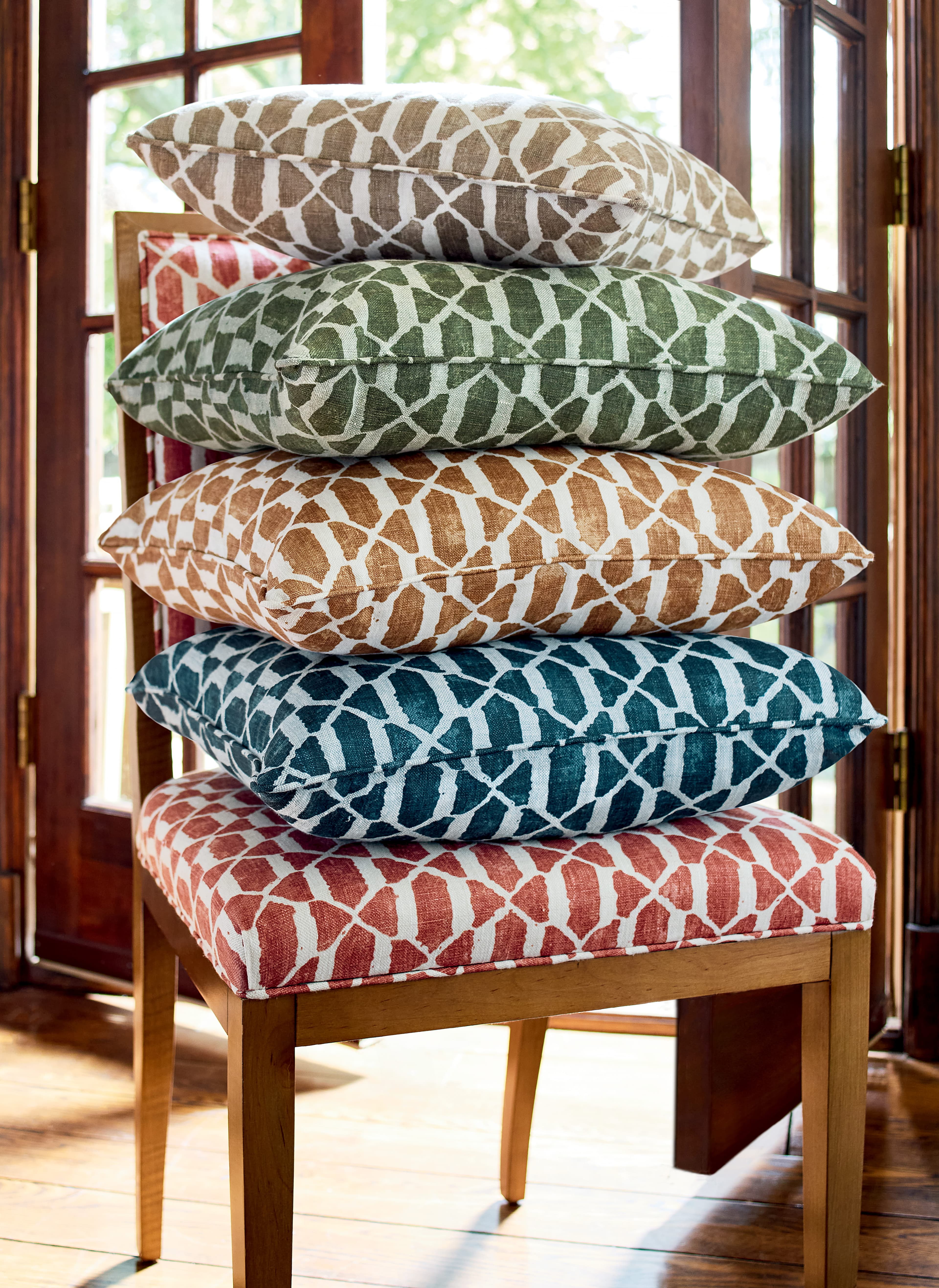 Vortex fabric colour story — stacked patterned pillows on chair